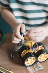 Close-up of boy making robotic toy on table at home - ALBF01533