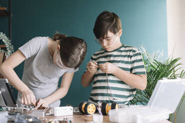 Siblings making robotic toy on table at home - ALBF01535