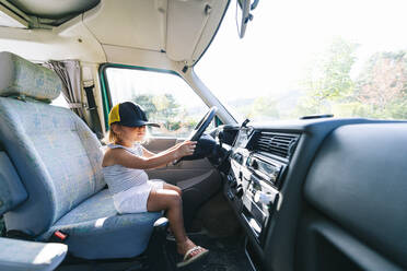 Mädchen mit Mütze auf dem Fahrersitz eines Wohnmobils - JCMF01345