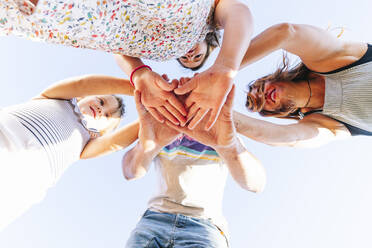 Parents stacking hands with daughters while standing against sky - JCMF01357