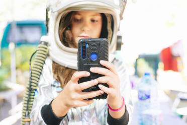 Close-up of girl wearing space suit taking selfie with smart phone - JCMF01365