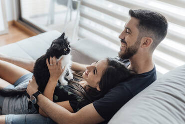 Happy couple spending leisure time with cat while sitting at home - SASF00069