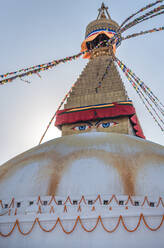 Niedriger Winkel des alten buddhistischen halbkugelförmigen Denkmals mit Ornamenten und dekorativen Augen auf dem Turm mit kleiner Kuppel und Girlanden auf der Spitze unter dem Himmel am Nachmittag - ADSF15251