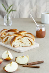 Von oben frische Brioche aus Butterteig mit Marmelade auf einem Holzbrett neben einem Glas Marmelade - ADSF15313