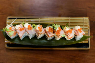 Von oben: leckere Röllchen mit Reis und Fisch, garniert mit Kaviar und Käsesoße, auf dem Tisch eines Luxusrestaurants - ADSF15384