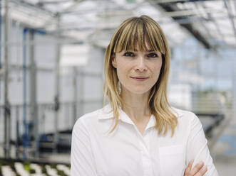 Close-up of confident businesswoman with blond hair standing in plant nursery - JOSEF01653