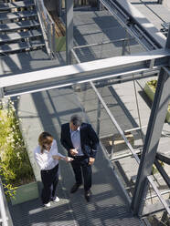 Colleagues discussing over digital tablet while standing in greenhouse - JOSEF01674