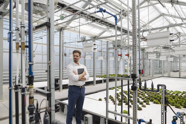 Male entrepreneur with digital tablet standing in plant nursery - JOSEF01757