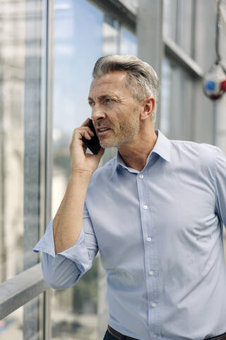 Close-up of male entrepreneur talking over smart phone in greenhouse stock photo