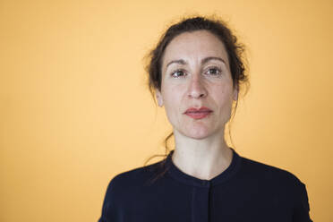 Close-up of female entrepreneur against orange wall - JOSEF01942