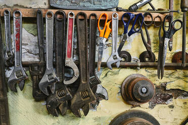 Satz verschiedener Werkzeuge mit verschiedenen Schraubenschlüsseln und Scheren an einer Betonwand im Atelier - ADSF15430