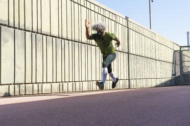 Von oben African American Sportler läuft schnell in der Nähe schäbigen Gebäude während des Trainings auf der Straße Stadt - ADSF15518