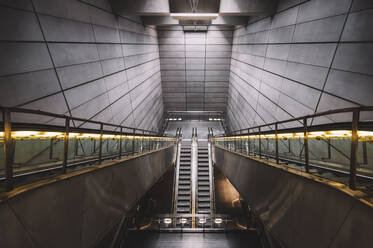 Innenraum einer leeren U-Bahn mit zeitgenössischer schmaler Rolltreppe in der Nähe der Wand aus Rechtecken und Boden mit glänzender Oberfläche mit künstlichem Licht an der Decke - ADSF15584