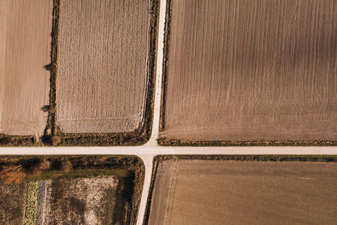 Luftaufnahme von oben einer Kreuzung, die durch ein landwirtschaftliches Feld in einer ländlichen Gegend führt, an einem Sommertag - ADSF15595