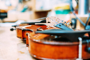 Modern shiny violin placed on shabby table in bright store with musical instruments - ADSF15613