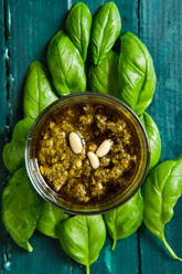 Draufsicht auf eine kleine Glasschale mit der berühmten italienischen Pesto-Sauce aus frischen Basilikumblättern und Pinienkernen, die mit Olivenöl übergossen ist - ADSF15660