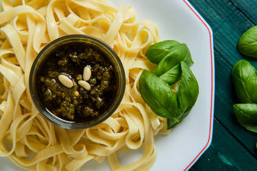 From above of yummy tagliatelle with Italian pesto sauce on top decorated with crunchy pine nuts and fresh basil leaves - ADSF15662