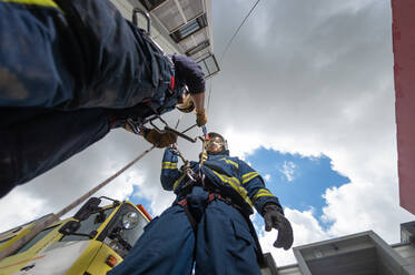 Von unten: Feuerwehrleute stehen in einem weitläufigen Gebäudekomplex und bereiten sich mit Seilen auf das Training vor - ADSF15674