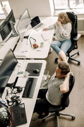 High angle view of male and female computer programmers sitting at table in office - MASF19490