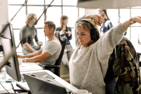 Female entrepreneur stretching while looking at computer in office - MASF19494