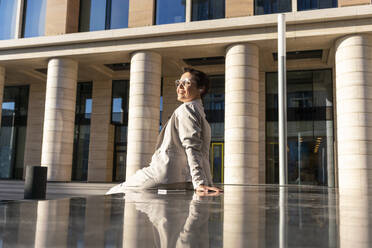 Businesswoman resting while sitting on bench against building - VPIF03005