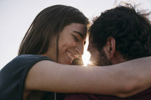 Woman smiling while embracing against clear sky stock photo