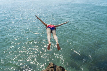 Mittlerer erwachsener Mann, der an einem sonnigen Tag ins Meer springt - AFVF07233