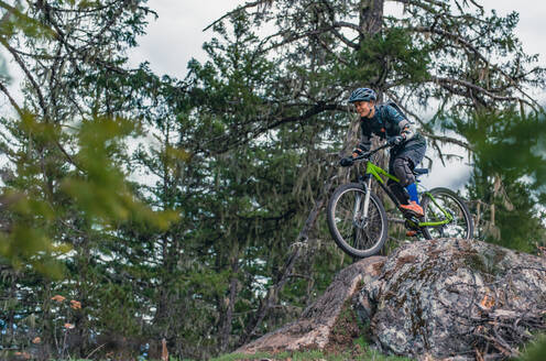 Frau beim Mountainbiking in einem Wald in den kanadischen Bergen - CUF56552