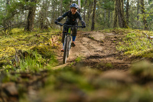 Frau beim Mountainbiking in einem Wald in den kanadischen Bergen - CUF56553