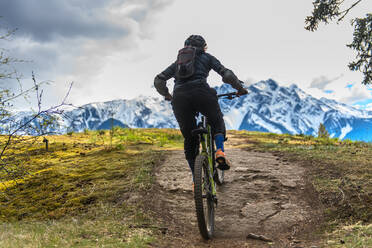 Frau beim Mountainbiking in einem Wald in den kanadischen Bergen - CUF56557