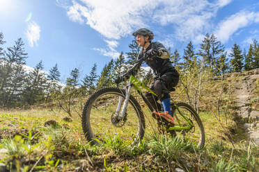 Frau beim Mountainbiking in einem Wald in den kanadischen Bergen - CUF56560