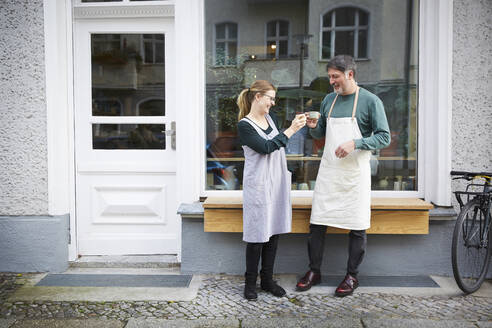 Lächelnde männliche und weibliche Kollegen beim Kaffeetrinken vor dem Kunstatelier - MASF19549