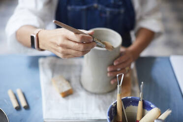 Midsection of mature woman learning pottery in art class - MASF19572