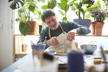 Mature man making craft product in pottery class - MASF19581