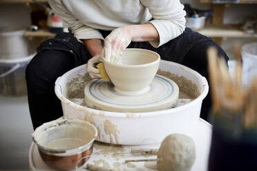 Midsection of mid adult woman molding pot in pottery class - MASF19587