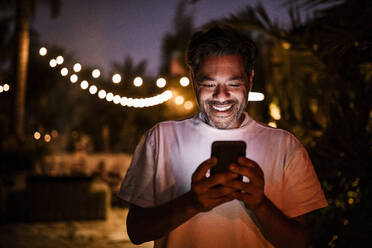 Happy man texting during sunset - MASF19624
