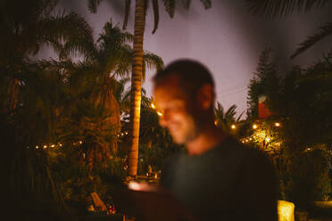 Smiling man using phone against trees during sunset - MASF19631