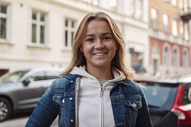 Portrait of happy teenage girl standing in city during weekend - MASF19655