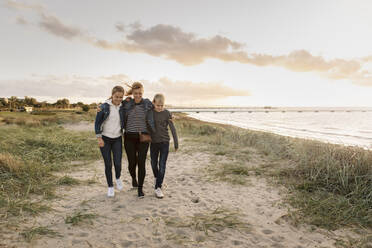 Smiling mother and children walking at beach during weekend - MASF19676