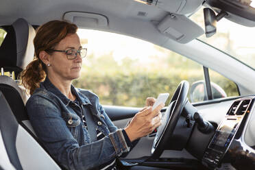 Mature woman texting while sitting in car - MASF19680