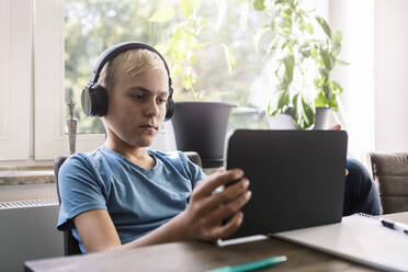 Male teenager studying on digital tablet at home - MASF19714