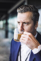 Businessman drinking tea while looking away at workplace - MASF19766