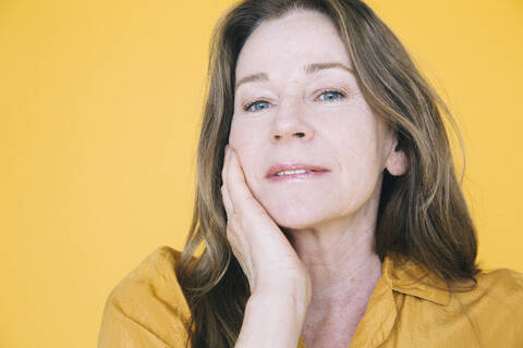 Portrait of senior woman against yellow background stock photo