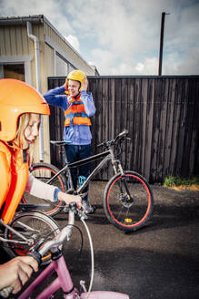 Bruder trägt Helm, während seine Schwester morgens Fahrrad fährt - MASF19930