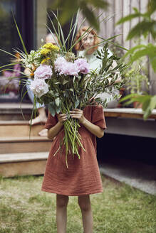 Girl holding flowers while standing in yard - MCF01286