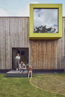 Parents and daughter spending leisure time outside tiny house - MCF01313