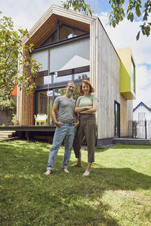 Glückliches Paar, das vor einem kleinen Haus posiert - MCF01314