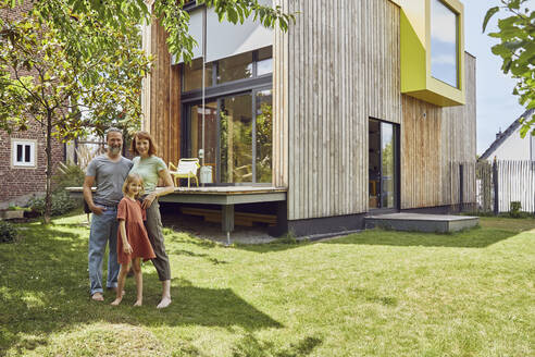 Family standing outside tiny house in yard - MCF01324