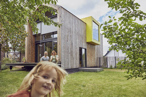 Smiling girl with parents in background at yard - MCF01338