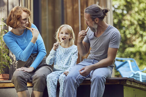 Family brushing teeth while sitting outside tiny house - MCF01414